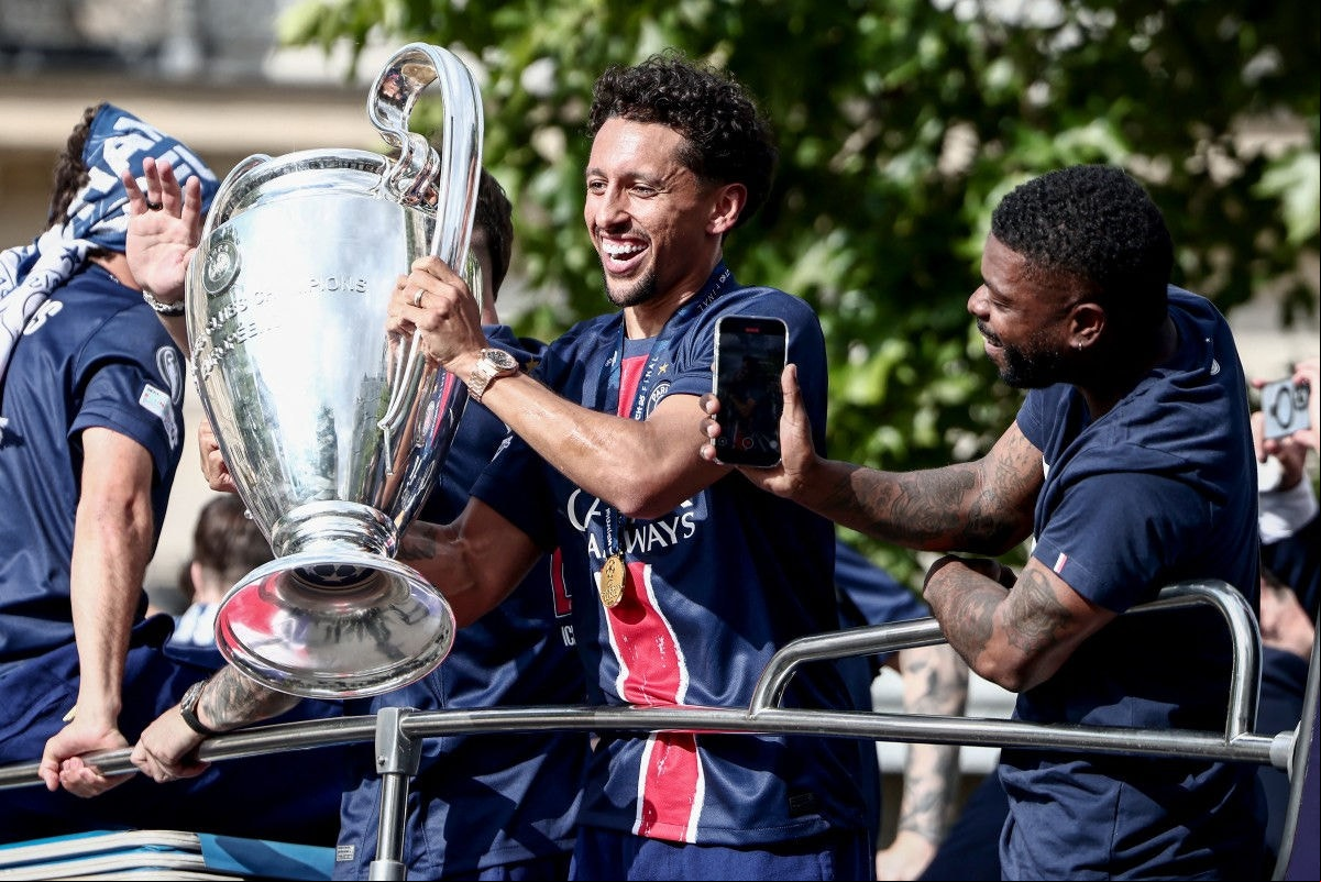 Paris Saint-Germain's Brazilian defender #05 Marquinhos (C) holds the UEFA Champions League Trophy during a parade on the Champs-Elysees avenue in Paris on June 1, 2025, a day after PSG won the 2025 UEFA Champions League final football match against Inter Milan in Munich. (Photo by Thibaud MORITZ / AFP)